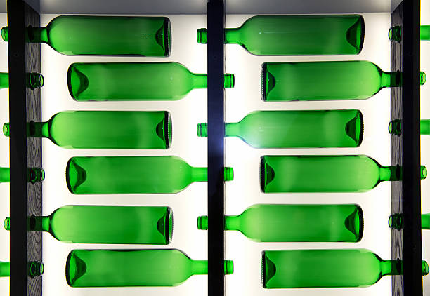 Decorative pattern of green glass bottles arranged in rows facing in alternating directions with back lighting