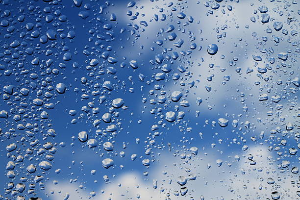 istock Rain drops on window with blue cloudy sky in background 504537196