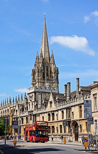 Oxford, United Kingdom - June 17, 2014:  All Souls College and the spire of the University Church of St Mary to rear with people walking along High Street, Oxford, Oxfordshire, England, UK, Western Europe.