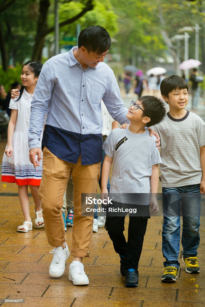 Group of Children with Adults A group of children walks through a park in Hong Kong, China. 8-9 Years Stock Photo