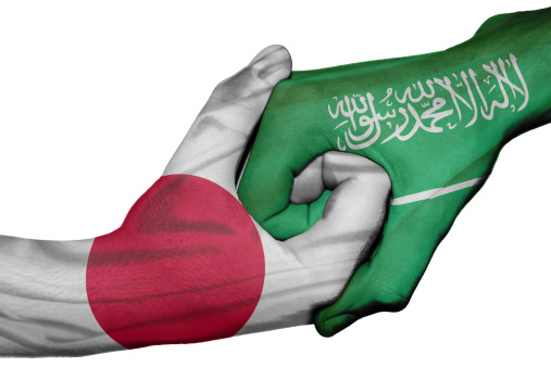 Diplomatic handshake between countries: flags of Japan and Saudi Arabia overprinted the two hands