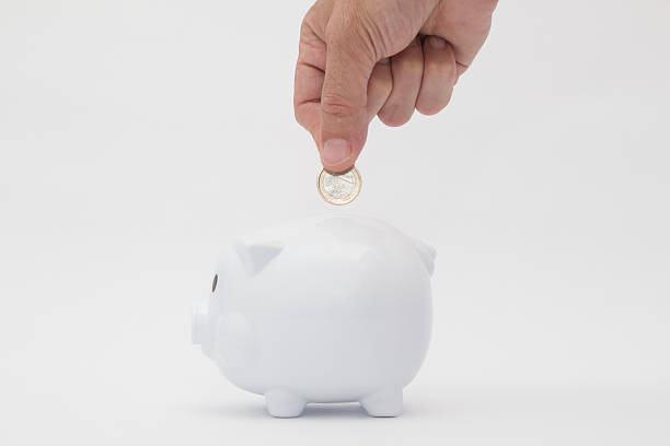 Piggy bank Piggy bank with hand tossing a coin. White background. ganar stock pictures, royalty-free photos & images