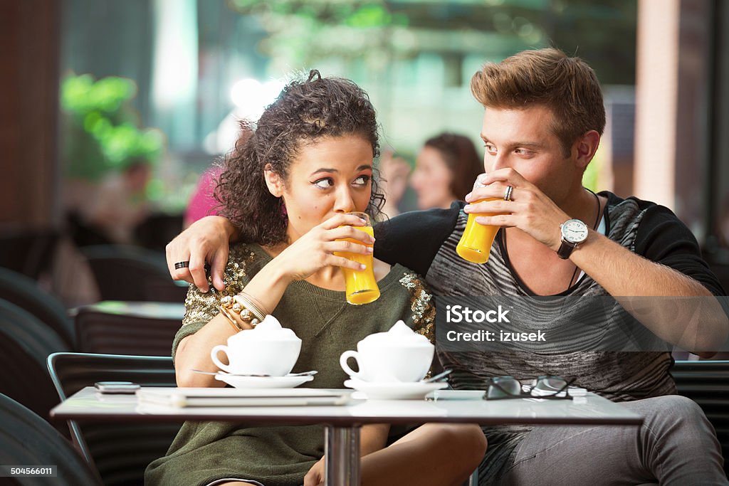 Urban young people in cafe Cheerful young couple dating in cafe, drinking orange juice. 20-24 Years Stock Photo