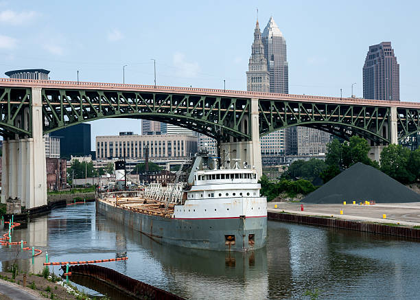 Upbound On The Cuyahoga A Great Lakes bulk carrier freighter laden with aggregate material navigates the narrow and winding Cuyahoga River passing under the Hope Memorial Bridge with part of downtown Cleveland, Ohio in the background river cuyahoga stock pictures, royalty-free photos & images