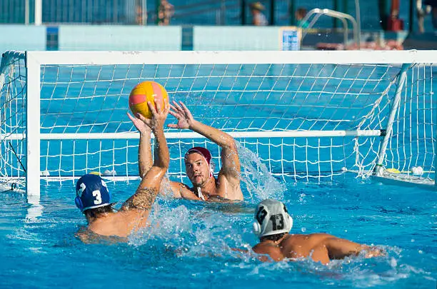 Shot of young water polo players having goal action