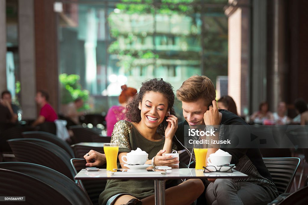 Urban young people in cafe Cheerful young couple sitting in cafe, listen to the music together. University Stock Photo
