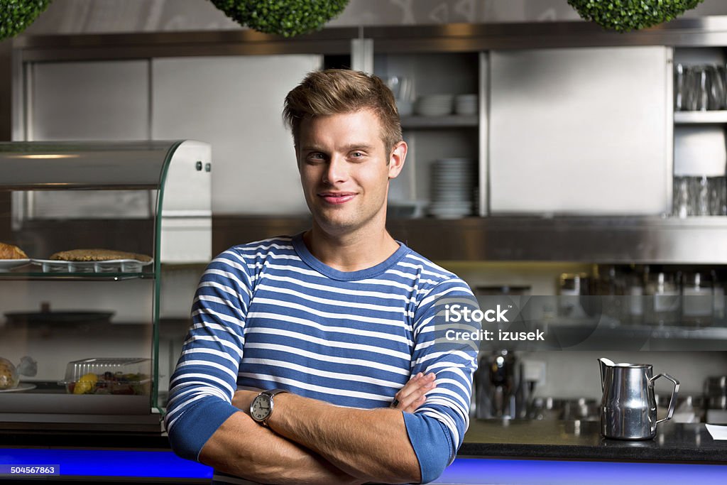 Coffee shop owner Friendly young man standing in front of the bar counter in coffee shop and smiling at camera. 20-24 Years Stock Photo