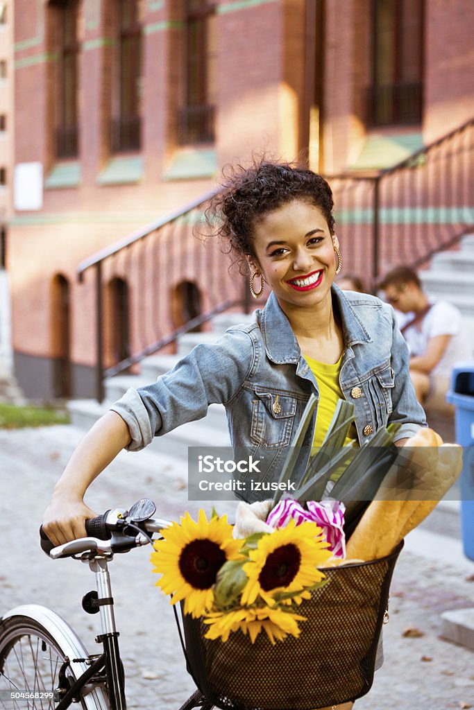 Happy female cyclist Young woman standing with bicycle with groceries in basket and smiling at camera. Bicycle Stock Photo