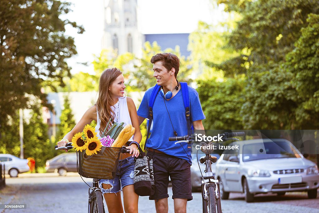 Cheerful urban young couple Outdoor portrait of urban young couple walking the street with blicycles and talking. 20-24 Years Stock Photo
