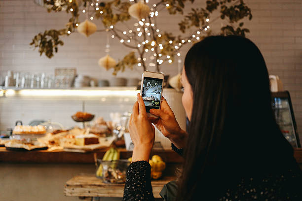 brunette joven tomando una foto con un teléfono inteligente - restaurante fotos fotografías e imágenes de stock