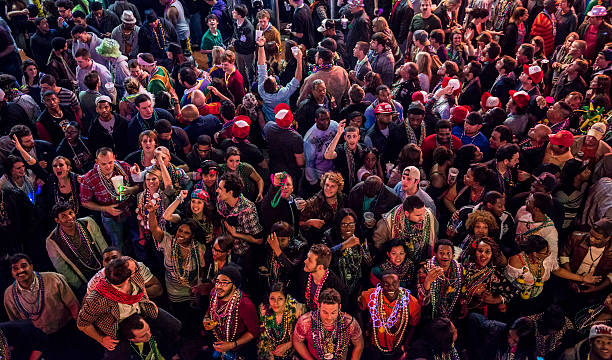 A large crowd of Mardi Gras revelers fill Bourbon Street in New Orleans, Louisiana.