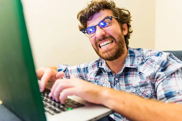 This is a horizontal, color, royalty free stock photograph of an angry, opinionated, young American man in his 30s writing on Internet forums in Orlando, Florida. He is wearing a plaid shirt and has a beard. Photographed with a Nikon D800 DSLR camera.