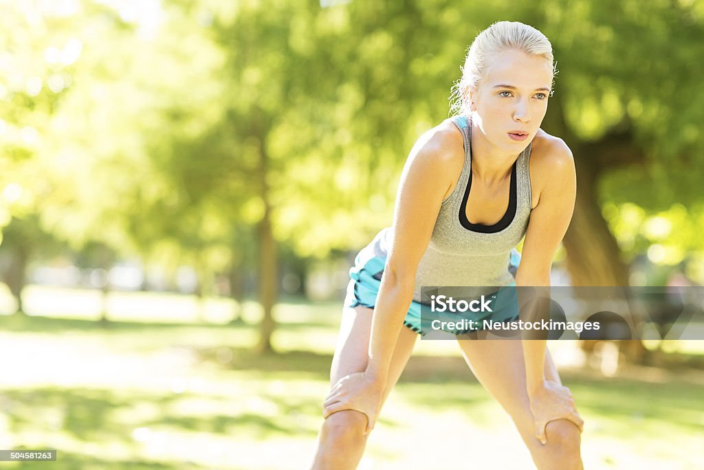 Tired Woman Taking Break While Exercising In Park Tired young woman taking break while exercising in park. Horizontal shot. 20-24 Years Stock Photo