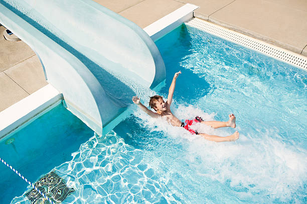 istock Boy Exiting Water Slide into Swimming Pool 504582461