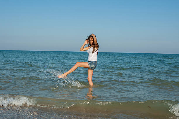 Giovane ragazza spruzzi d'acqua in mare - foto stock