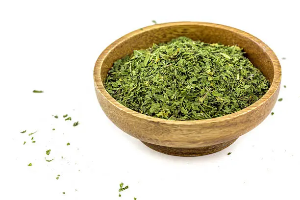 Dried Nettles in a wooden bowl on a white background.