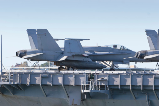 A navy jet fighter on the deck of an aircraft carrier
