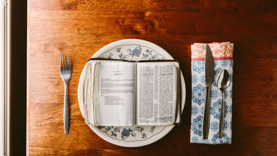 Bible on Table with Knife & Fork to show the idea of fasting.
