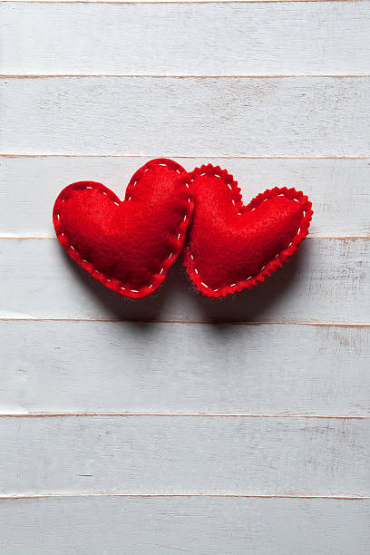 Dois corações de algodão vermelho em um rústico parede - foto de acervo