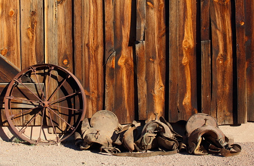 Old wild west  wooden barn with horse saddle and wagon wheel
