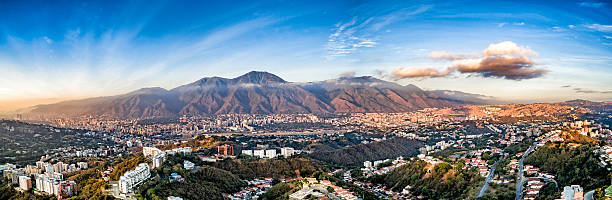 Panoramic image of Caracas city aerial view with El Avila Panoramic image of eastern Caracas city aerial view at late afternoon. Venezuela.  Showing El Avila mountain also known as El Avila National Park (Guaraira Repano).  Santiago de Leon de Caracas, is the capital city of Venezuela and center of the Greater Caracas Area. It is located in the northern part of the country, following the contours of the narrow Caracas Valley and the "Cordillera de la Costa". The valley is close to the Caribbean Sea, separated from the coast by a steep 2,200 m (7,200 ft) high mountain range, Cerro El Avila. To the south there are many more hills and mountains with residential constructions. Caracas is divided into five municipalities: Libertador, Chacao, Baruta, Sucre, and El Hatillo. Libertador holds many of the government buildings and is the Capital District (Distrito Capital). The Metropolitan Region of Caracas has an estimated population of 5,250.000. caracas stock pictures, royalty-free photos & images