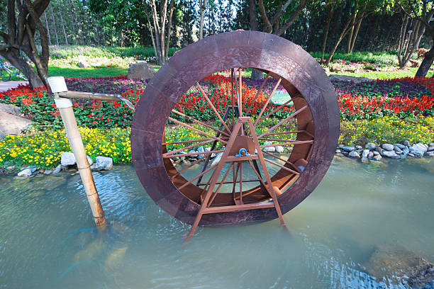 Architectural landscape of the Yunnan Nationalities Village in China, with a waterwheel in the forest