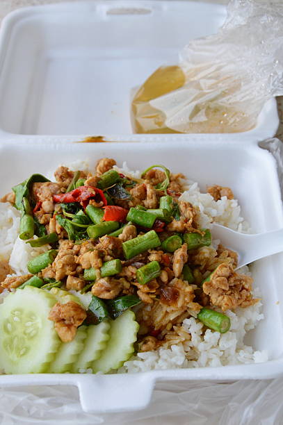 spicy stir fried chicken with basil leaf on rice in foam box for take home