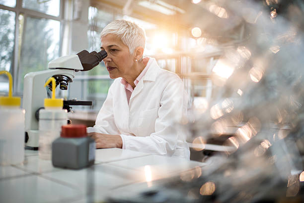 fêmea farmácia analisar algo através de um microscópio no laboratório. - women scientist indoors science imagens e fotografias de stock