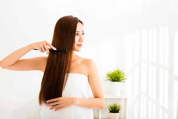 joven hermosa mujer peinar su cabello en la sala de estar - hair care combing women human hair fotografías e imágenes de stock
