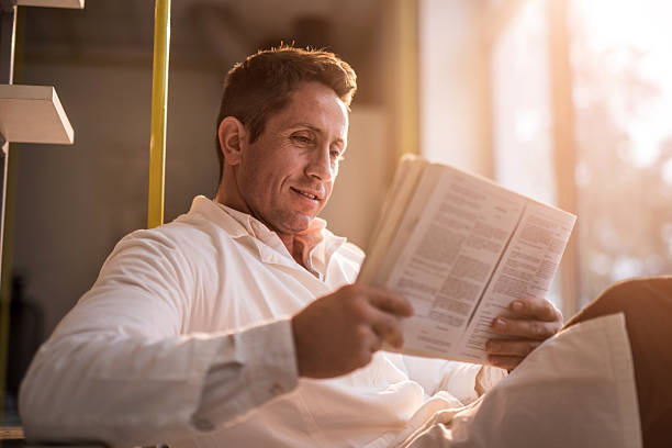 istock Smiling male doctor relaxing while reading a book. 504615474