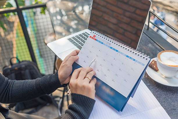 istock Woman’s hand carrying calendar and pointing on it by pen 504617250