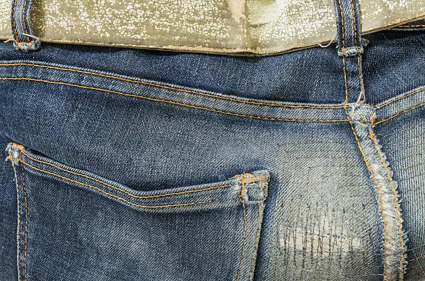 Closeup at old and repaired jean trousers background