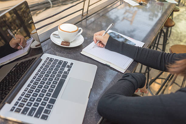 istock Woman hand writing on notebook with laptop and cappuccino 504632386