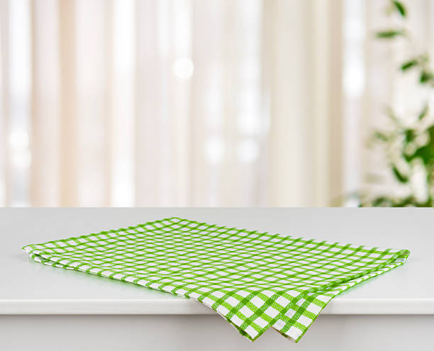 Green checkered kitchen towel on table over defocused curtain background Green checkered kitchen towel on table over defocused curtain background tablecloth photos stock pictures, royalty-free photos & images
