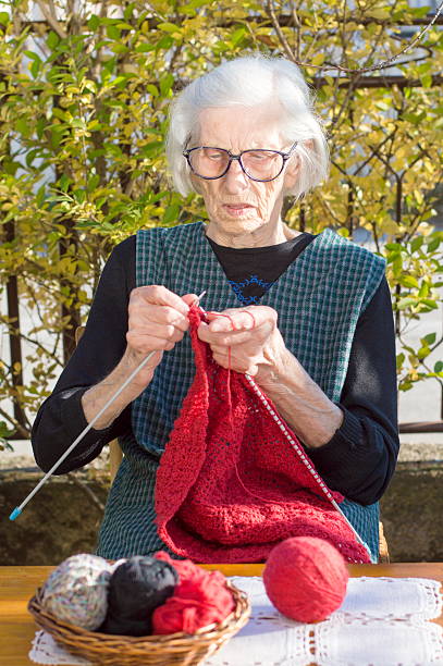 istock 90 years old woman knitting a red sweater 504639946