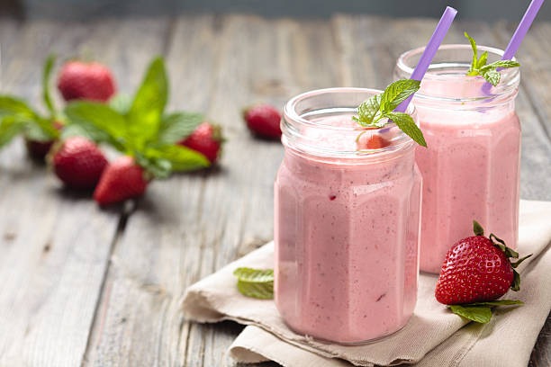 Strawberry milkshake. Fruit smoothie with mint leaves on wooden rustik table milkshake stock pictures, royalty-free photos & images