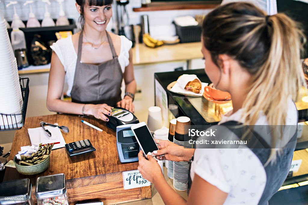 Contactless payment in the cafeteria Woman paying with her mobile phone for her breakfast at a coffee Shop. Australia Stock Photo