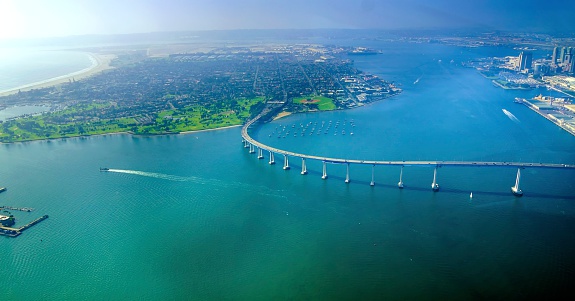 Aerial view of the Coronado island and bridge in the San Diego Bay in Southern California, United States of America. A view of the Skyline of the city and some boats crossing the the sea.