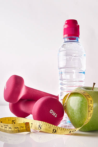 istock Apple dumbbells tape and bottle on white table front isolated 504644536
