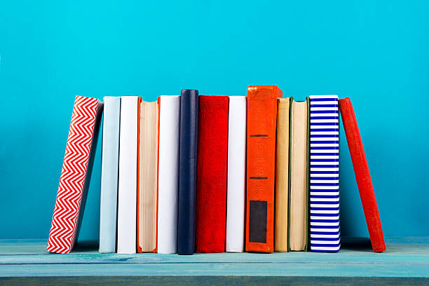 Row of colorful hardback books, open book on blue background