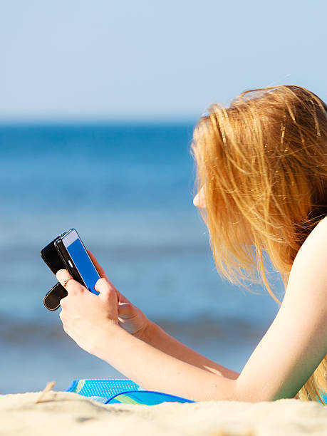 istock Summer vacation Girl with phone tanning on beach 504652081
