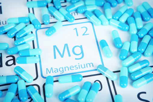 Magnesium with capsules or pills on the periodic table (Periodic table made by me)  Stock image representing mineral supplementation.