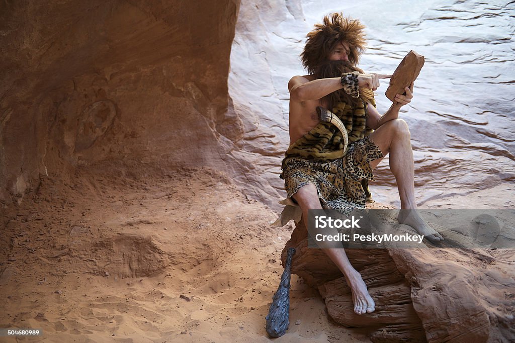 Homem das Cavernas sentado ao ar livre com pedra Tablet com ecrã táctil - Royalty-free Homem das Cavernas Foto de stock