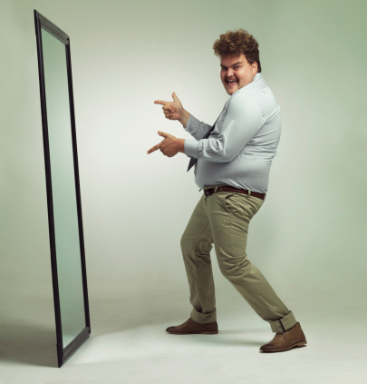 Shot of an excited overweight man celebrating while looking in a mirror