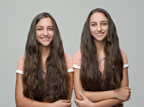 Two twin teenage sisters smiling at camera