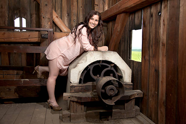 Woman in a white dress climbs up the ladder inside the old attic