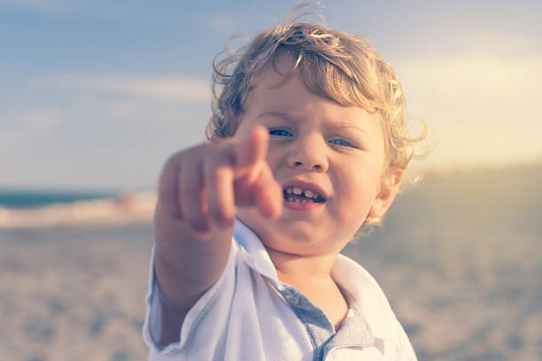 istock Boy on the beach pointing finger to a camera 504684423