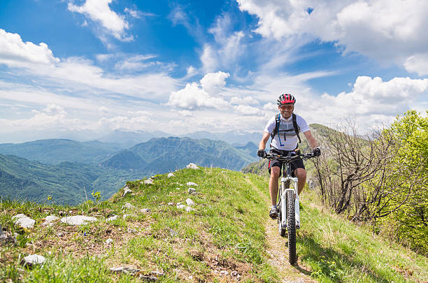 A male mountainbiker is enjoying his ride along a rim in the Friulian Mounatins. Friuli is bordered on the west by the Livenza river, on the north by the Carnic Alps, on the east by the Julian Alps and the Timavo river, and on the south by the Adriatic Sea. The northern part of the region is completely mountainous.