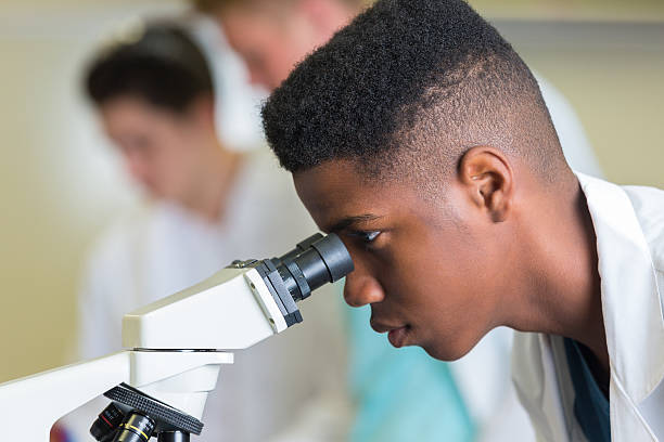 High school boy using microscope during science class High school boy using microscope during science class teenagers only teenager multi ethnic group student stock pictures, royalty-free photos & images