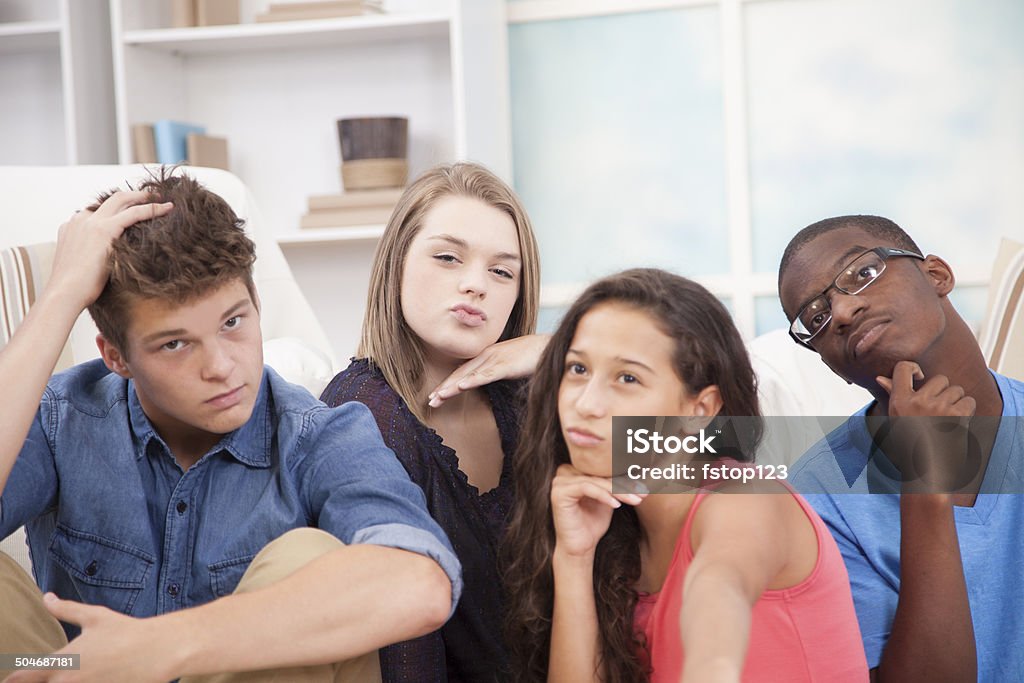 Teenager friends 'strike-a-pose' to take a silly selfie!  Home. Teenager friends "strike a fun pose" and take a silly selfie photo with their cell phone, which is held out of view by Latin descent girl in foreground.  Multiracial Group Stock Photo